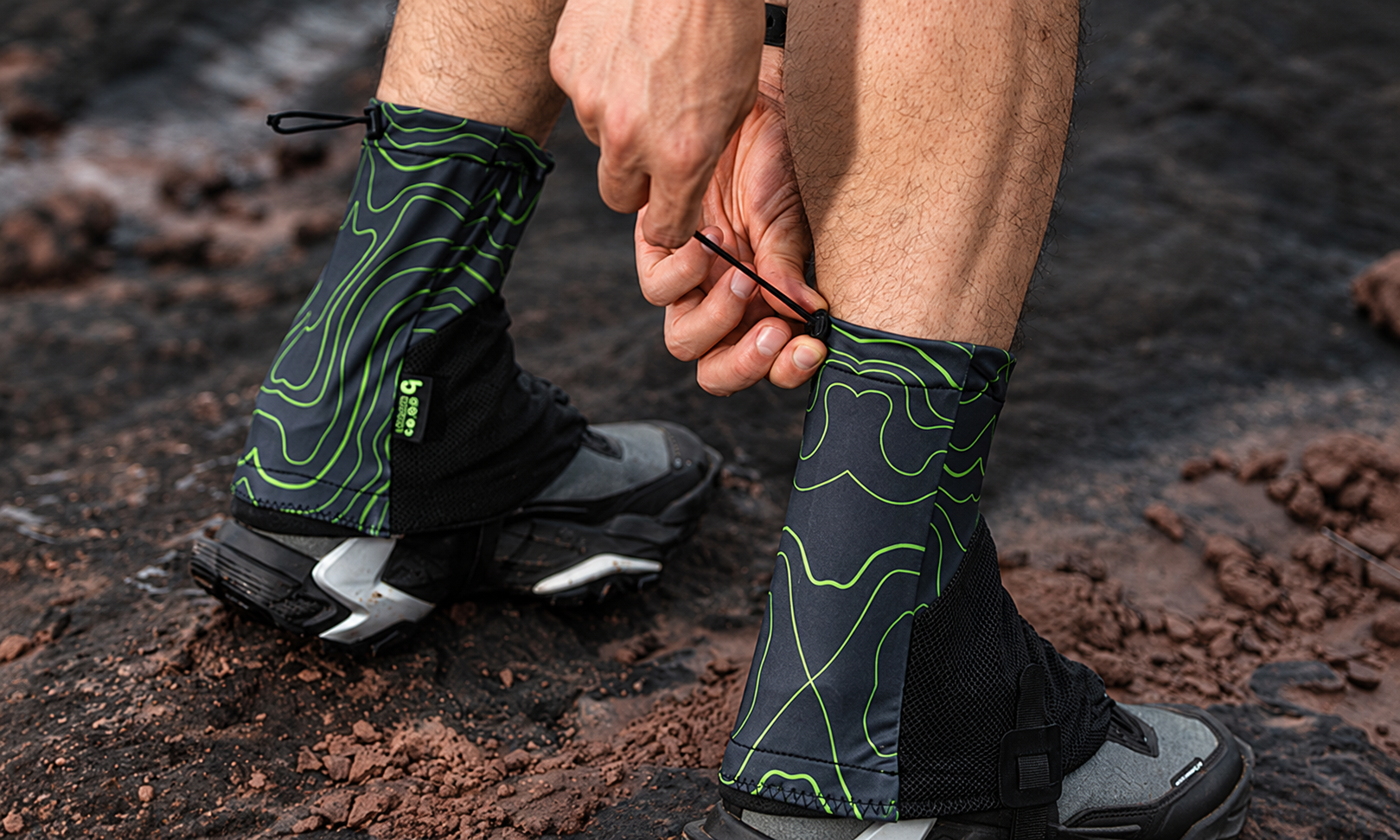 Hand adjusting the drawcord at the top of a contour-pattern gaiter